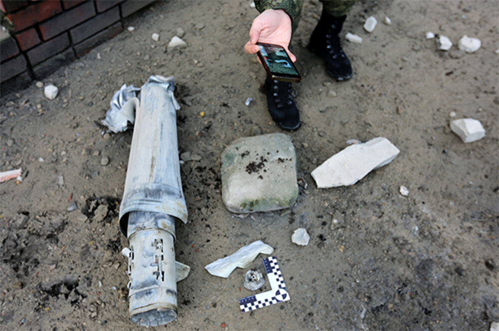    Представитель СК РФ фиксирует фрагмент разорвавшегося снаряда от РСЗО «Град» на улице Постышева в Ворошиловском районе Донецка после обстрела со стороны ВСУ. Фото: РИА/ Сергей Аверин