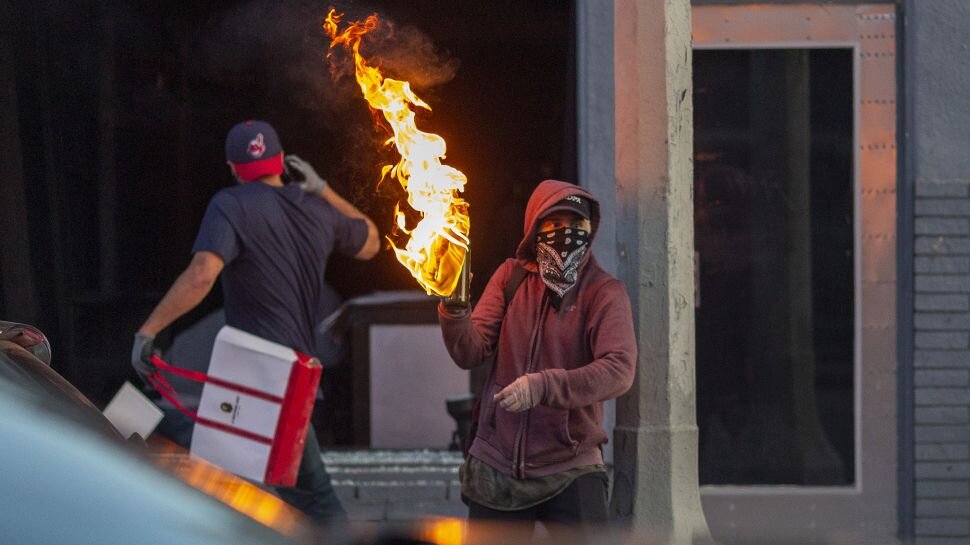 Мужчина бросает коктейль молотова во время протестов, последовавших за смертью Джорджа Флойда в 2020 г.