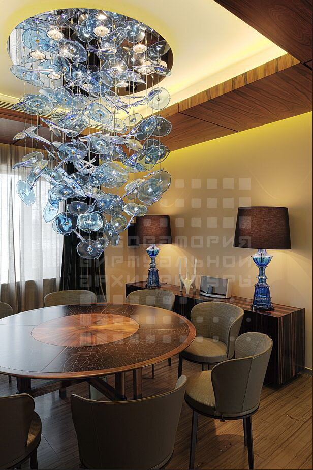 столовая группа загородного дома, использован крупный акцентный, но при этом прозрачный светильник и настольные лампы, несмотря на преувеличенные размеры, из-за прозрачности не давят