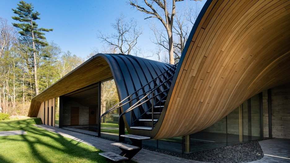 Современный дом с изогнутым деревянным фасадом в лесах Канады