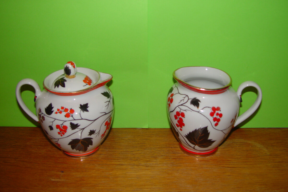 Носик слева (ранняя форма начала пятидесятых) резче очерчен. Есть кольцо с подставкой (или кольцевая полочка) для крышки. Всего этого нет на молочнике справа. Роспись изменилась, но осталась в прежнем стиле. Кстати, роспись полностью ручная! Единственно, что абсолютно совпадает и там , и там - форма и роспись ручек, и размер донца.