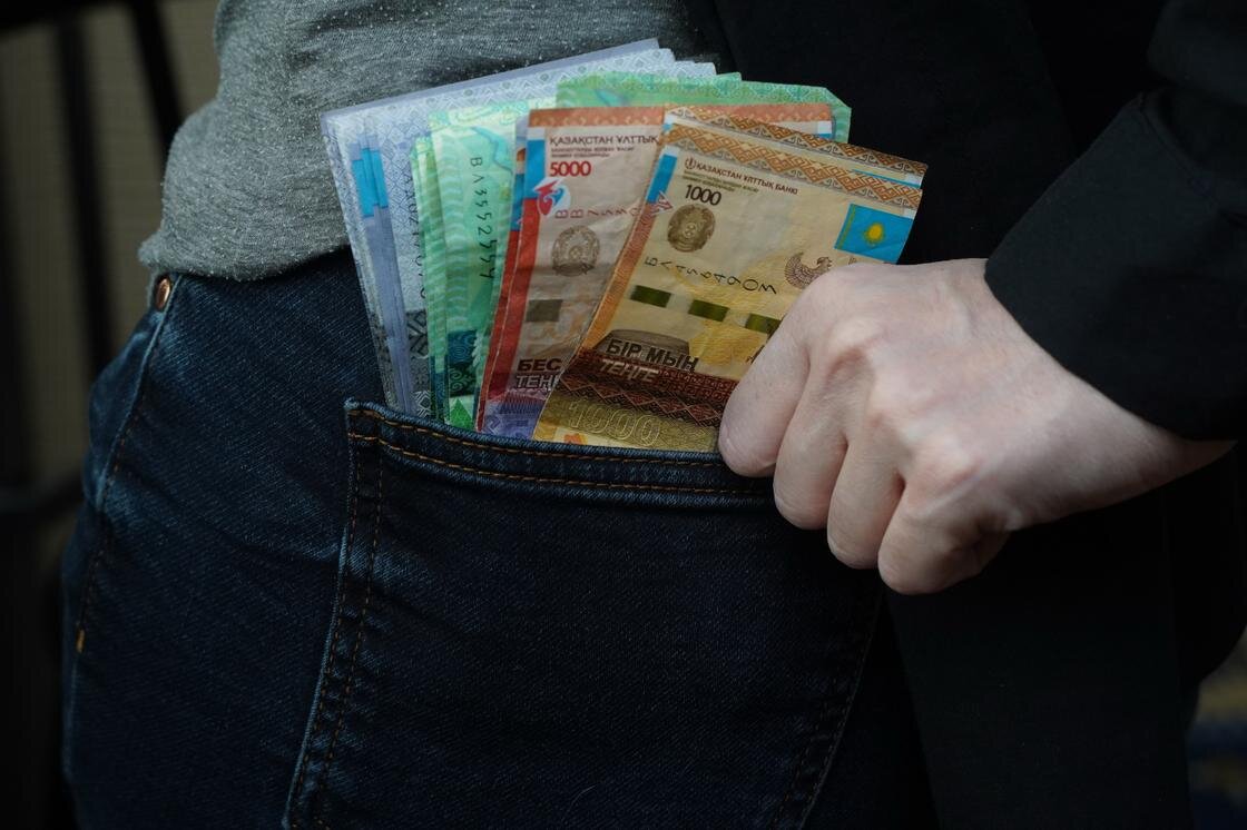    Мужчина кладет деньги в задний карман:NUR.KZ/Владимир Третьяков