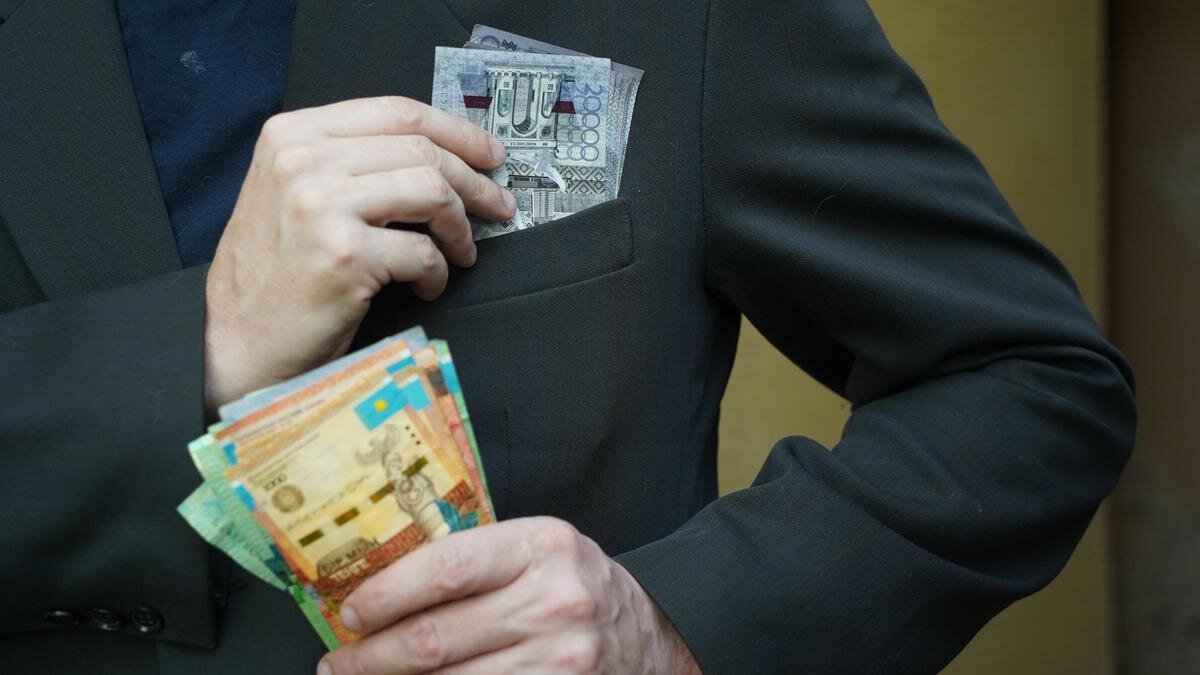    Мужчина кладет деньги в нагрудный карман:NUR.KZ/Владимир Третьяков