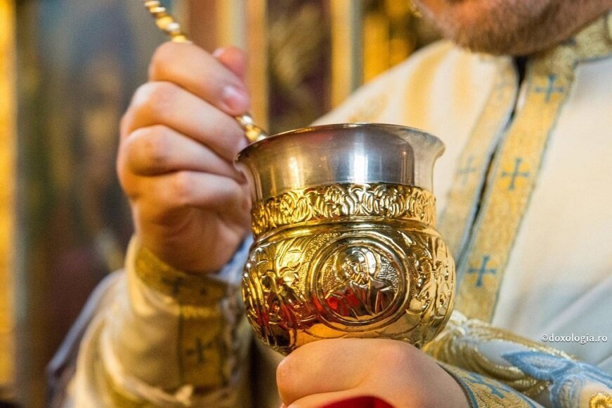 Потир и лжица в руках священника на причастии
