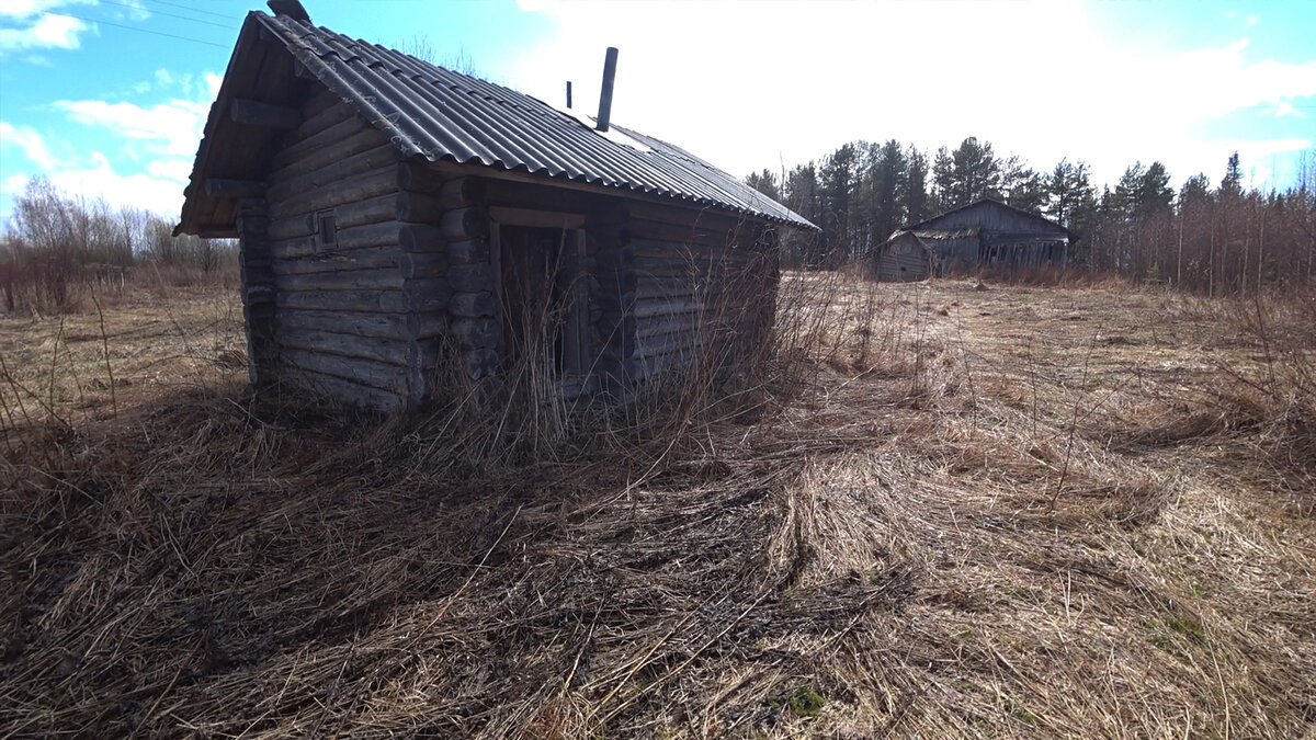 Баня на заброшенном участке, в далеке виден дом-пятистенок