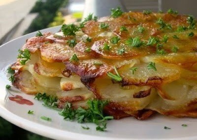 Картофель "Анна" (фр. "pommes anna") - классическое французское блюдо. Картофель для него нарезается очень тонкими кружочками, укладывается слоями в сковороду или в форму и готовится на сливочном масле в духовке или на плите до зажаристой корочки. Готовое блюдо выглядит как запеканка или пирог с красивым узором из картофельных кружочков наверху. В классическом варианте ингредиентов всего три: картофель, сливочное масло и соль, но возможны и другие добавки, например, лук-шалот, петрушка или даже белые грибы. Конечно же, как и большинство таких простых и старомодных французских блюд "без наворотов," картофель "Анна" невероятно вкусен и душевен. Ингредиенты:
1200 - 1300 г картофеля (5-6 больших клубней)
110 г сливочного масла
3 луковицы лука-шалота (или зеленого лука, только белые части)
соль и молотый черный перец по вкусу
мелко нарезанная петрушка для подачи (по желанию)
Превращаем обычное сливочное масло в топленое. Для этого растапливаем масло в маленькой кастрюльке на среднем огне и кипятим примерно две минуты, пока пена с масла не осядет.
Процеживаем масло через марлю, фильтр для кофе или бумажное полотенце.

Лук-шалот или зеленый лук нарезаем очень тонкими кружочками.Картофель чистим и тоже нарезаем очень тонкими кружочками, примерно по 1 или 2 мм толщиной.Круглую форму для запекания очень хорошо смазываем топленым маслом. (Можно также для страховки застелить ее дно промасленной бумагой.) Укладываем в форму слой картофельных кружочков "внахлест." Солим, перчим, смазываем сливочным маслом. Посыпаем нарезанным луком.Таким же образом выкладываем слои из оставшихся кружочков картофеля, слегка посыпая каждый слой солью, перцем и нарезанным луком и смазывая маслом. Верхний слой картофеля также солим, перчим и смазываем маслом. Ставим в разогретую до 215 C (420 F) духовку на один час.
Кстати, во Франции для приготовления такого картофеля существуют специальные "двухдонные" формы, которые можно переворачивать, чтобы картофель более равномерно пропитывался сливочным маслом, и чтобы хрустящая румяная корочка образовалась и сверху, и снизу. Но и в обычной форме в духовке все хорошо получается.
Вынимаем картофель из духовки. Лопаткой проверяем, не прилип ли нижний слой картофеля ко дну формы. Накрываем форму большой плоской тарелкой и аккуратно переворачиваем всю эту конструкцию. Даем постоять пару минут. Аккуратно снимаем форму. Низ запеканки, таким образом, становится ее верхом.

Посыпаем (по желанию) мелко нарезанной петрушкой и подаем. Можно такой картофель подать и на гарнир к чему-нибудь мясному, и как самостоятельное блюдо вместе с большим овощным салатом.