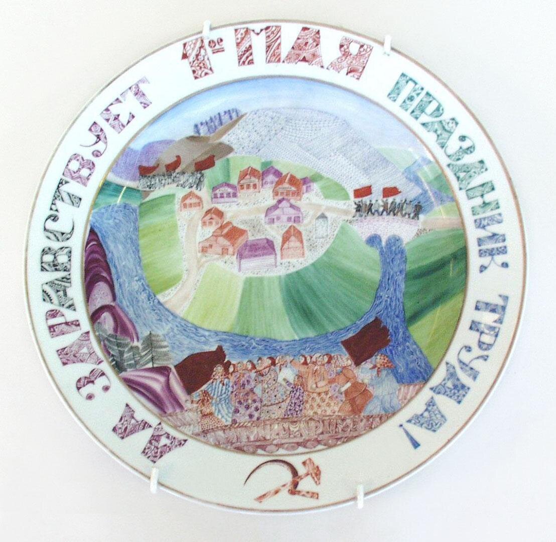 Блюдо "Да здравствует 1 Мая - праздник труда!" 1932. Роспись надглазурная полихромная, позолота. Размеры: 5,2*35 см. Собрание Эрмитажа. Предмет поступил в 2002-м году. Передан в составе коллекции Музея Фарфорового завода. Инв. номер Мз-С-1239. Изображение взято из каталога Эрмитажа. 