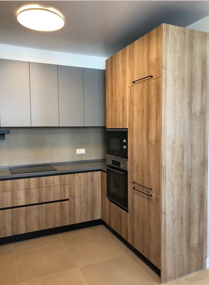 Кухонный гарнитур в ЖК Вернисаж сделан по дизайн-проекту дизайнера Земова Дмитрия в рамках компании БИС-интерьер. Все фасады гарнитура МДФ в ПВХ покрытии с имитацией дерева и однотонный серый цвет