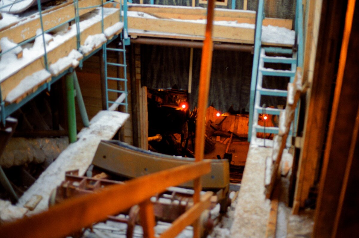 Форма наклонного хода с трудом угадывается за загромождением строительных лесов. На переднем плане - процесс опускания тюбинга к месту проведения работ.