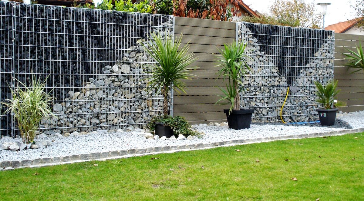 Забор из темных и светлых камней в сетке
