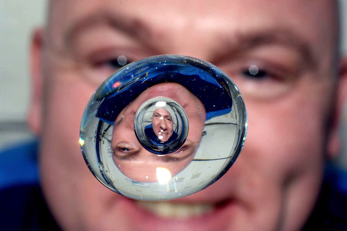 Астронавт ESA Андре Койперс фотографируется через каплю воды с пузырьком внутри. Фото: NASA/ESA
