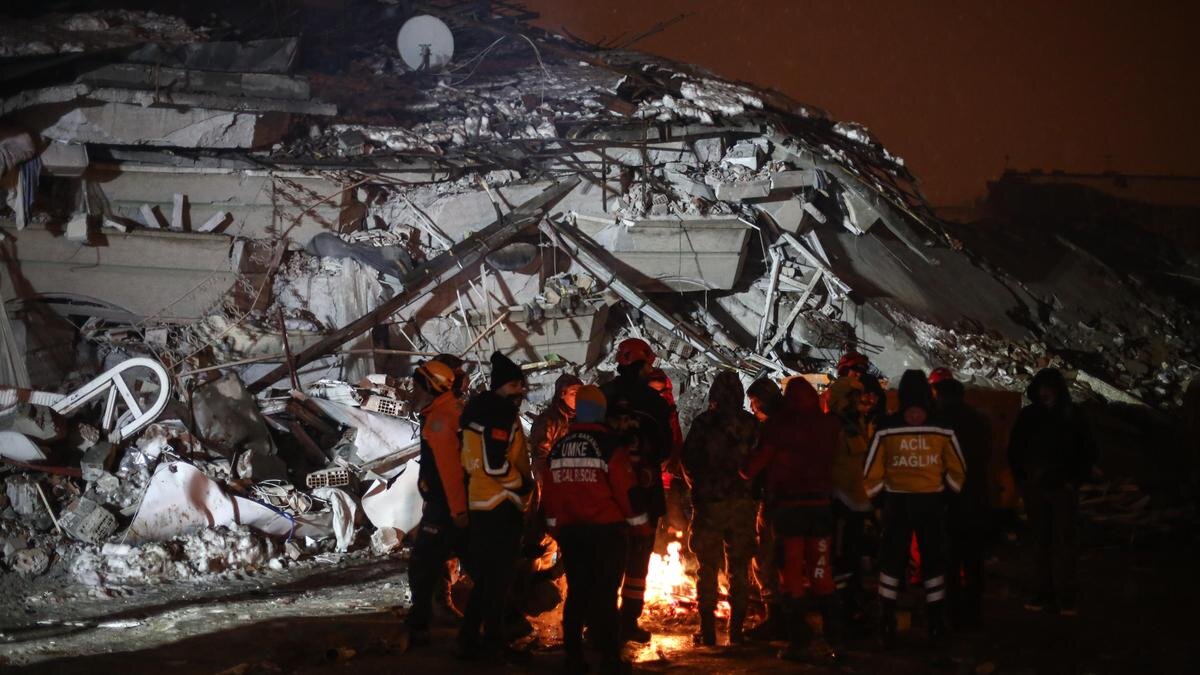    Спасатели в Кахраманмараше греются у костра:Hakan Akgun/ dia images via Getty Images