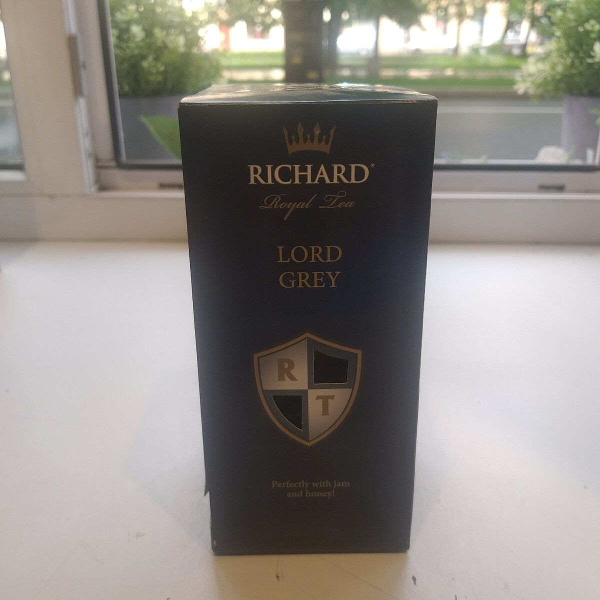 Сегодня королевский чай Ричард производится российской компанией «МАЙ», которая объединяет в себе 5 разных направлений бизнеса. Производством горячих напитков занимается МАЙ-Foods. В список продукции компании также входят чаи известных торговых марок: Лисма, Майский, Curtis.

В каком году появился чай Ричард на полках отечественных магазинов? Компания «МАЙ» запустила свой новый бренд в 2014 г. Тогда изготовили первую партию чая Richard и начали поставлять его во все регионы нашей страны. Сегодня продукцию этого бренда производитель представляет как «имеющий королевскую историю английский чай высокого качества».

На заметку! В настоящее время компания «МАЙ» является обладателем собственных представительств в таких «чайных» странах, как Шри-Ланка, Индия и Кения. Благодаря этому в Россию поставляется сырье хорошего качества. Также МАЙ-Foods имеет сертификат соответствия стандарту ISO 9001:2015 от BSI.

Ассортимент и виды

Продукция Ричард подразделяется на виды в зависимости от степени ферментации чайного листа, типа его обработки и упаковки. В ассортименте зеленый и черный Richard (в том числе с добавками). Королевский чай фасуется в отдельные коробки (массой 90 и 180 г), пакетики, сашеты и подарочные жестяные банки (по 100 г).

Ассортимент продукции данного бренда разнообразен. Рассмотрим всю чайную коллекцию Richard.

