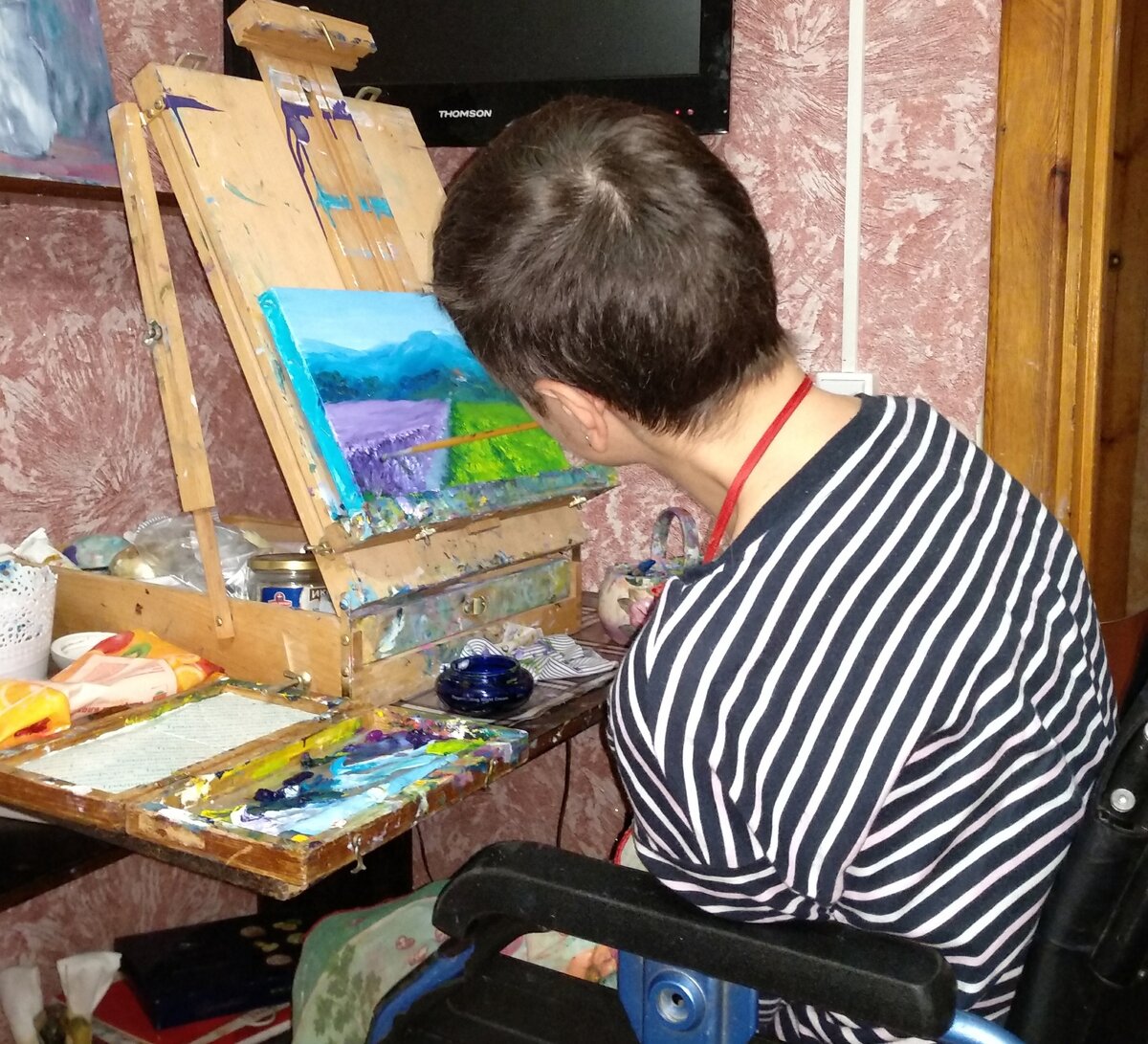 Ольга рисует, держа кисточку в зубах