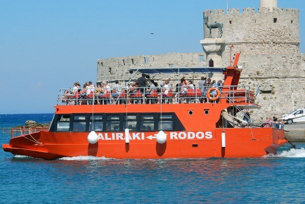 Мы поступили так: на пристани Фалираки купили тур  за 27 евро. В высокий сезон лучше покупать его заранее, в сентябре  мы купили без проблем прямо на борту. Тур включал в себя трансфер  на Faliraki Rhodes Sea Shuttle в порт Мандраки (отправление из Фалираки  в 7.50), билет на паром Sea Dreams (отправление из Родоса в 9.00, www.seadreams.gr)  и услуги русско-говорящего гида. В итоге получилось дешевле, быстрее  и организованнее, чем если бы мы добирались до Родоса на автобусе,  а потом покупали билет на паром. И уж тем более дешевле чем, если бы  мы брали подобный тур у отельного гида (у него он стоил 45 евро).