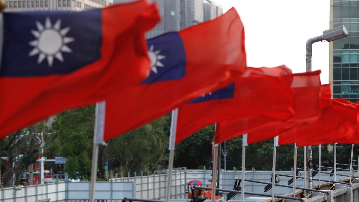    Женщина в маске идет по мосту, где развиваются флаги Тайваня:Ceng Shou Yi/NurPhoto via Getty Images