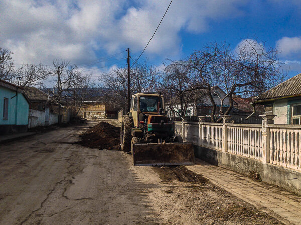 Трактор копает траншею, чтобы проложить газовую трубу.