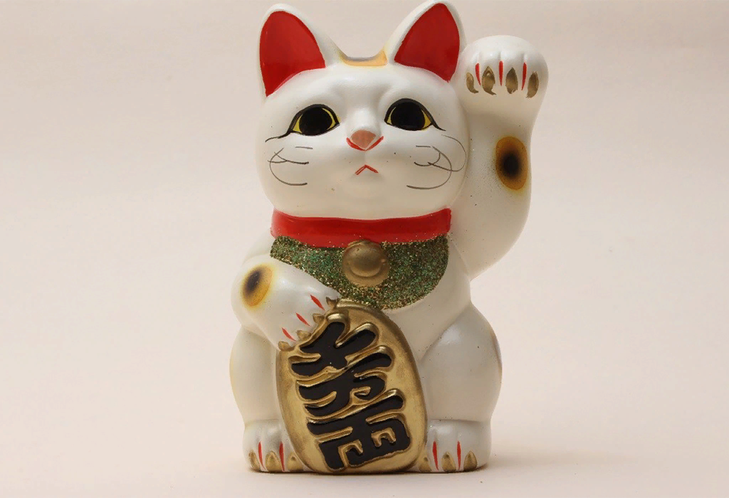 Кошка с поднятой левой лапкой символизирует доброжелательность, открытость и стремление к общению.