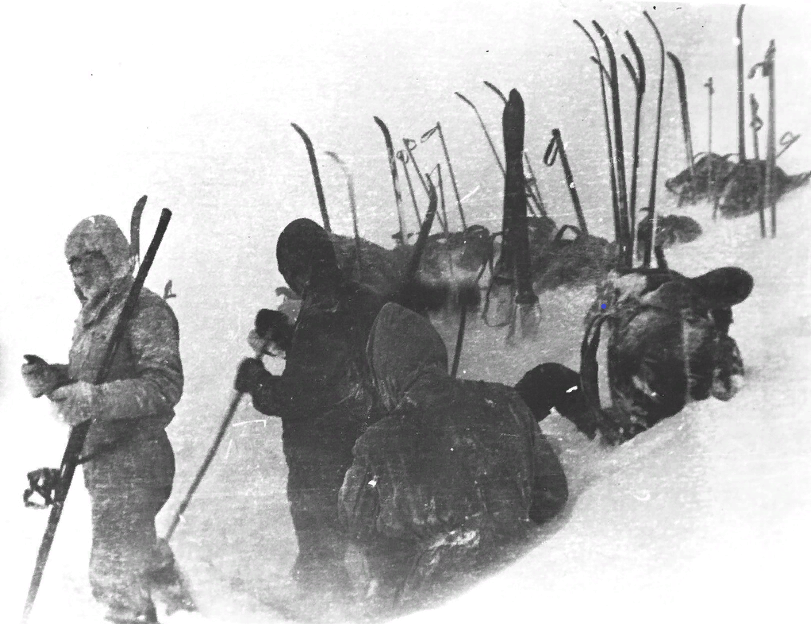 Фото "Установка палатки" с сайта Дятлов пасс. Крайний слева: Кривонищенко - на левом нагрудном кармане хорошо виден круглый значок, у него их было два: "Турист СССР" и круглый "Вторая спортивная категория". Вы можете видеть их на всех фотографиях. На поясе у него висит нож в ножнах. На фото не все туристы, часть отсутствует.