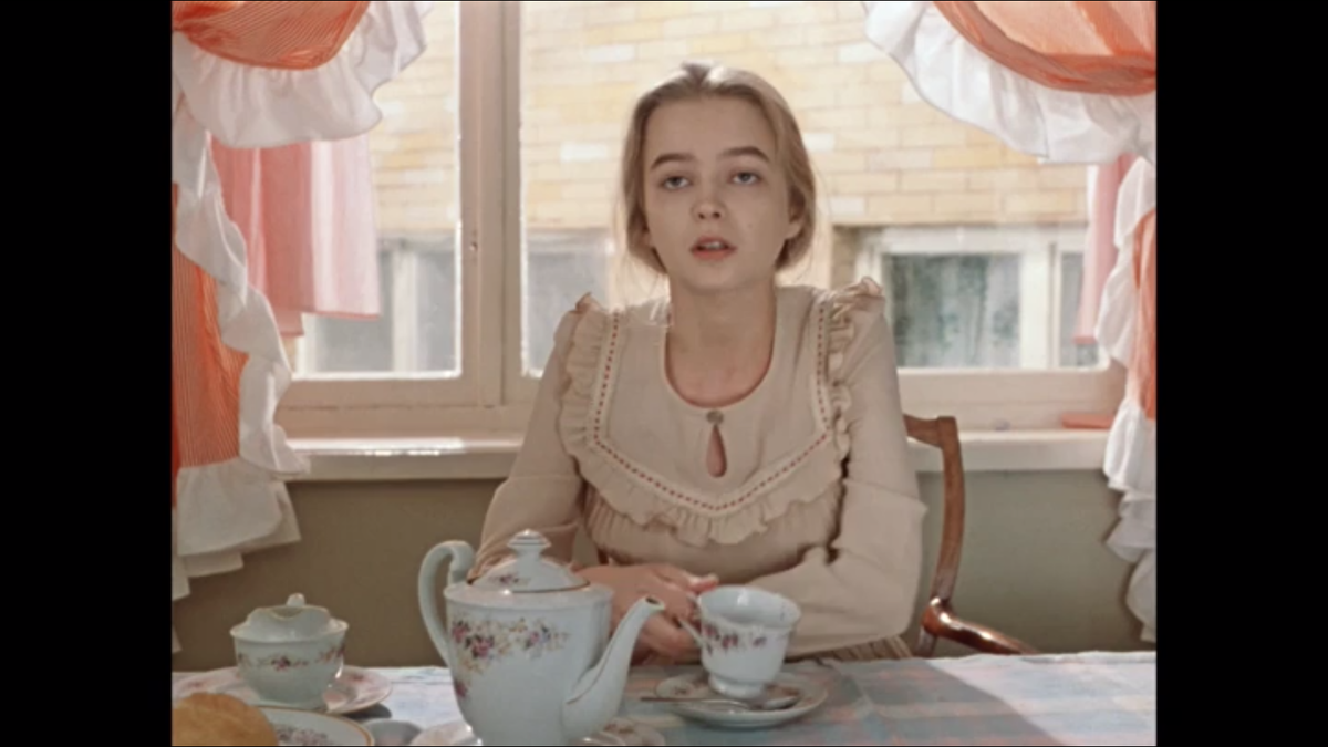 Александра носит очень нежное девичье платье, скорее всего, из тонкой синтетики, отделанное оборками на лифе. Цвет материала, оборка и маленький вырез капелькой подчеркивают юность и свежесть героини.