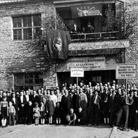 Майское митинг 1950-х гг. Интересная деталь в центре снимка: под транспарантом СЕПГ служащий размахивает флагом местного клуба рабочей гимнастики, спасенного из Никсдорфа.