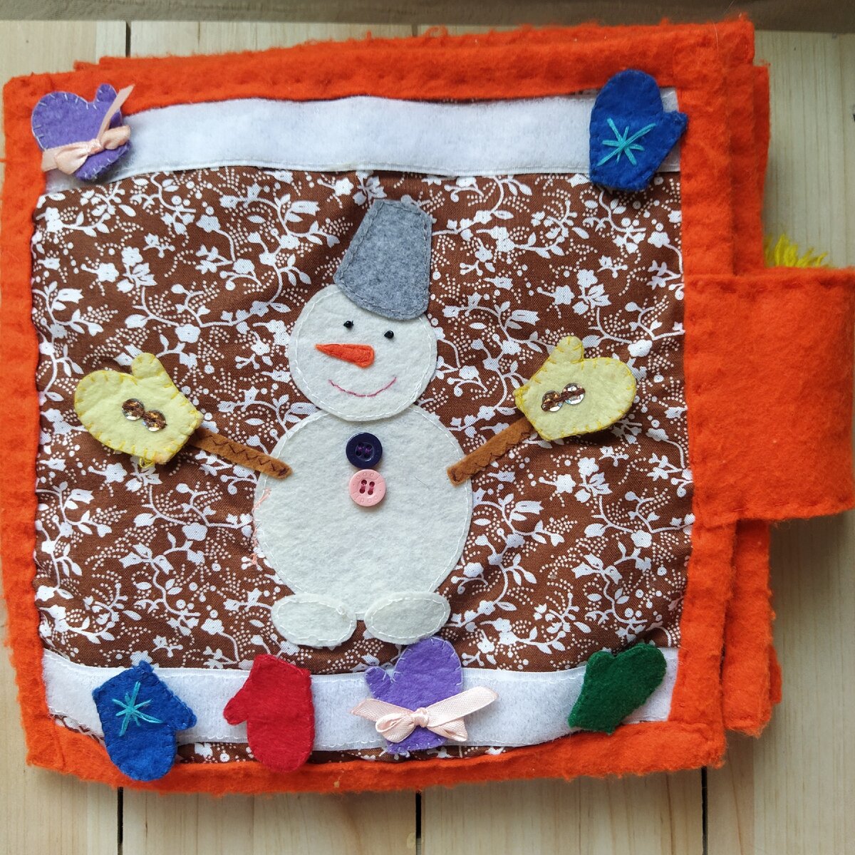 Книга сшита из ткани. Каемка и скрепляющая часть из фетра - его можно найти в любом тканевом магазине или отделе для рукоделия.  На этой странице нужно подобрать пару одинаковых рукавиц для снеговика. Рукавички на липучках.