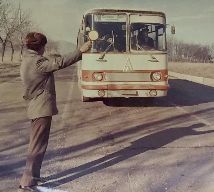 Контролер на дороге останавливает автобус