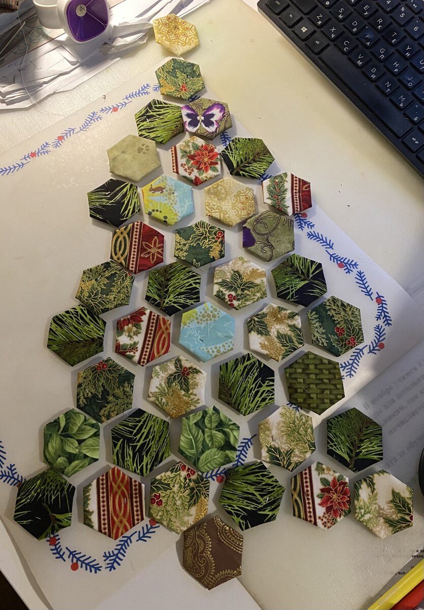 Из ткани нарезаем прямоугольники нужного размера.  Складываем сразу несколько слоёв заготовки вместе.
Сверху накладываем шаблон и ножом для пэчворка отрезаем всё ненужное.
Обрезков в таком раскрое получается очень мало.
Подготавливаем каждый гексагончик, доводим его до ума, подгибая и фиксируя с изнанки ниточкой припуски. Проутюживаем и вынимаем шаблончики. 
