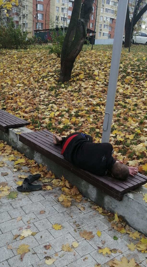 Бездомный спит на скамейке