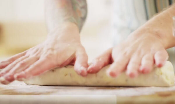 В емкость со всеми подготовленными ингредиентами добавляют муку, просеивая ее через ситечко. Все хорошенько вымешивают, формируют колбаску, разрезают ее на части. Каждый кусочек придавливают, обволакивает в муке. 