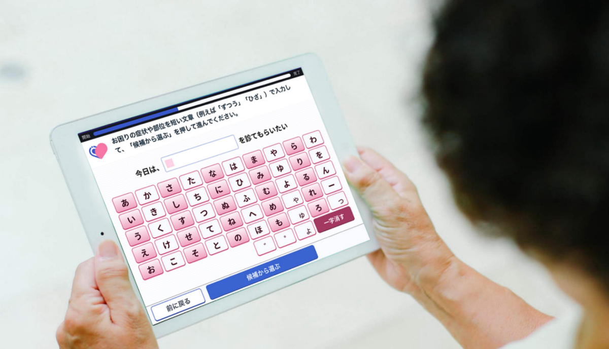 Программное обеспечение Ubie AI-medical interview assistance проводит предварительное интервью с пациентом, который взаимодействует с программным обеспечением через планшет, задавая вопросы о симптомах и медицинском анамнезе.