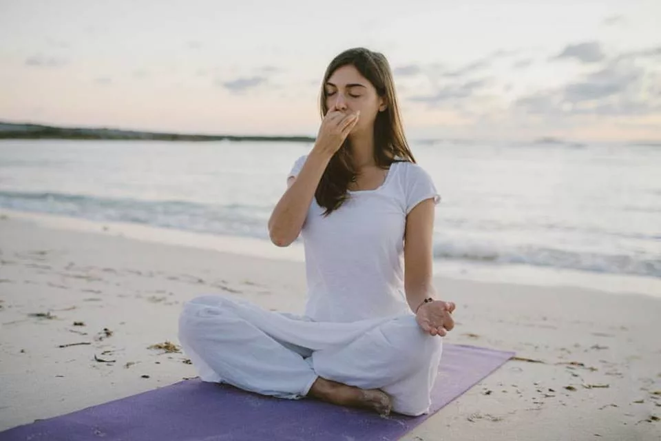 Девушка выполняет упражнение Пранайамы - поочерёдное дызание через разные ноздри