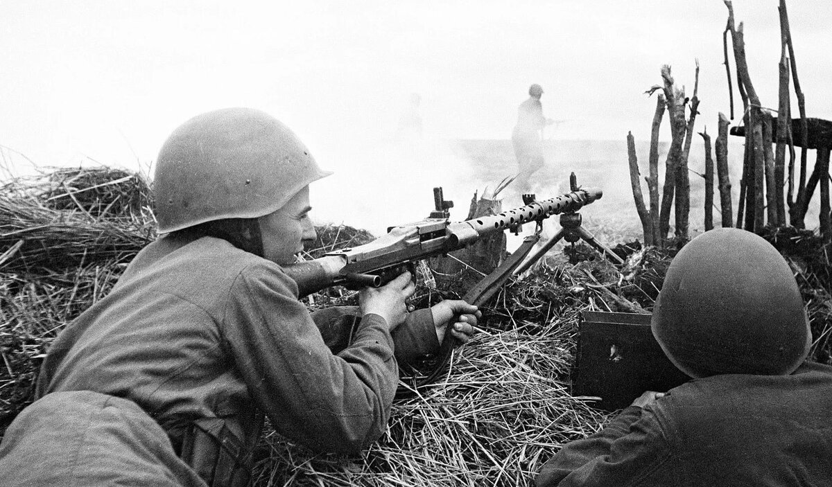 Солдат с пулемётом ведёт стрельбу лёжа.