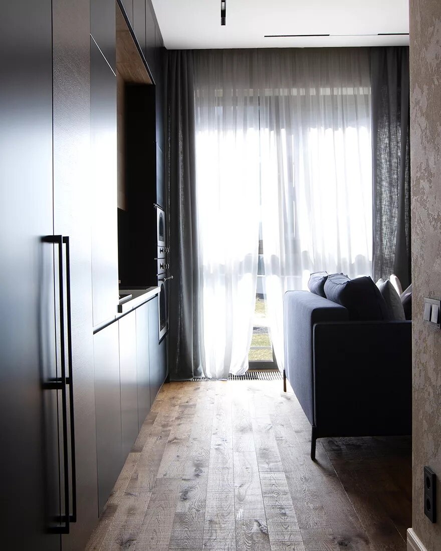 Диван развернули спинкой к проходу, чтобы обозначить границы гостиной. Рядом в углу расположили столовую группу. Её выделили панелями из кедра, отступы между ними намеренно сделали разными, чтобы разбить привычный ритм.