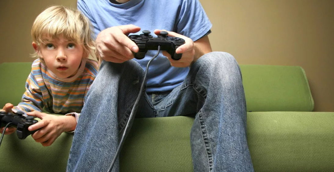 Папа с сыном играют в приставку.