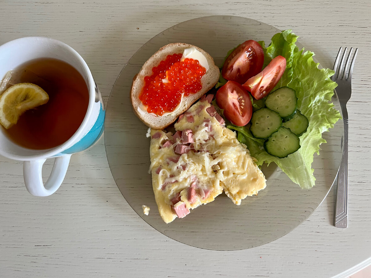 Омлет с колбасой , овощи, бутерброд и чёрный чай с лимоном. 