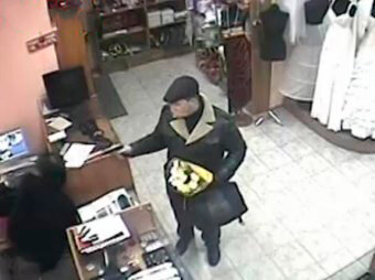 Кадр с камер видео наблюдения в свадебном салоне. В руке желтые хризантемы.  