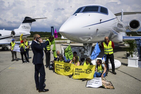 Экологические активисты организаций Stay Grounded и Greenpeace проводят демонстрацию, приковав себя наручниками к самолету во время Европейской конвенции и выставки деловой авиации (EBACE) в аэропорту Женевы в Женеве, Швейцария, 23 мая 2023 года. (Лоран Жильерон/Keystone через AP, файл)