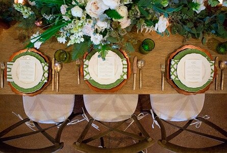 Экостиль остаётся трендом уже не один сезон, и даже год. Стремление ко всему натуральному сейчас вовсе не означает отказ от роскоши или аскетизм. Напротив – натуральные материалы нынче в цене и почете. Во-первых, потому что «эко» - это всегда полезно, а во-вторых, потому что натуральные материалы во многих странах лимитированы, и цена на них растет по мере увеличения дефицита.  Но на наш взгляд, природа и ее продукты – это в первую очередь красиво и очень атмосферно!

За основу в стиле «эко» берется натуральная древесина, текстиль и свежие цветы. Экостиль универсален: деревянный стол и посуда одинаково органично впишутся в стиль лофт и классик, в прованс и «скандинавию». Для скатерти выберите льняную или хлопчатобумажную ткань в оттенках, созвучных всему интерьеру, эко-сервировка не должна быть кричащей или чересчур претенциозной.

В качестве ярких акцентов используйте контрастные тканевые салфетки – длинные индивидуальные поперек стола или одну продольную в центре.

 

Фантазируйте с посудой. Не стоит останавливаться на традиционном фарфоре и стекле. Замените их на тарелки и подносы из бамбука, а стеклянные и хрустальные стаканы – на глиняные.

Не бойтесь зеленого декора! Пусть на столе будет много цветов и растений – и без того свежая и вкусная еда покажется гостям еще изысканней в сочетании с запахами трав или терпкостью хвои. В случае если цветочные ароматы не уместны (к примеру, у гостей аллергия) используйте декор из натурального мха – на столе он выглядит неожиданно, но очень нежно.

Фарфоровая или глиняная (даже не обожженная) посуда, деревянный и цветочный декор, натуральные ракушки или камешки – в правильном сочетании создадут изысканную и поистине свежую атмосферу. Не бойтесь переусердствовать – не обязательно ставить сразу все блюда и загромождать стол. Подавайте тарелки постепенно и передавайте блюда между гостями, голодными они не останутся.

Касательно самих блюд, лучше выдержать стилистику сервировки и отказаться от жирной и «тяжелой» пищи. Пусть на столе будет больше овощных закусок, запечённое мясо и натуральные напитки. Исключите традиционные для нашей страны «оливье» и заливное, пусть трапеза будет органичной во всех пониманиях.