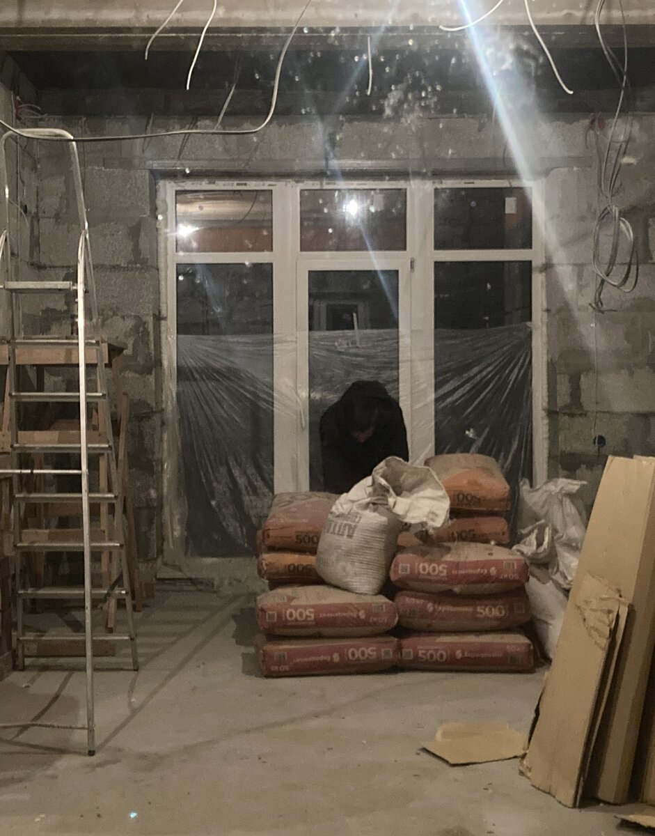 Строитель, склонившийся над мешками 