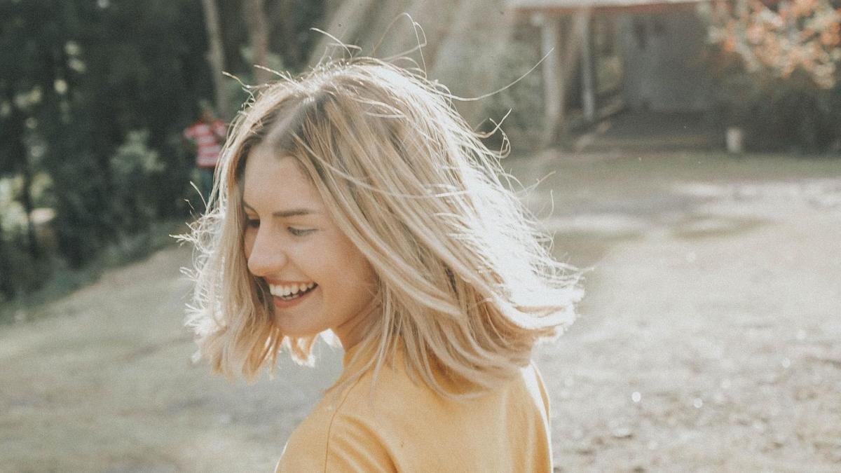    Девушка смеется в лучах солнца:Unsplash/Gian Cescon