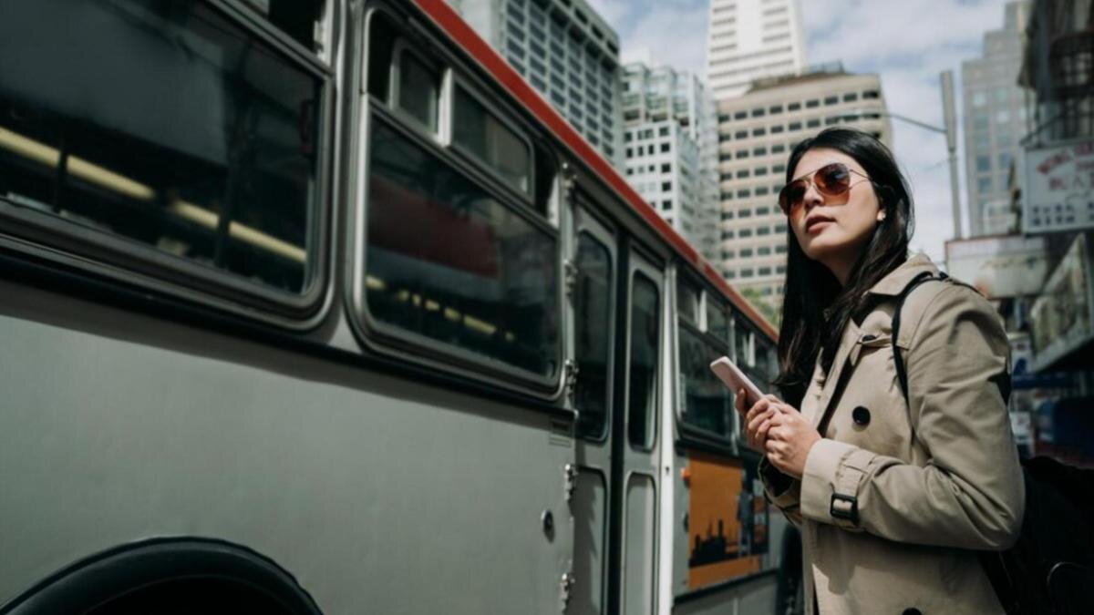    Девушка стоит возле автобуса:Freepik