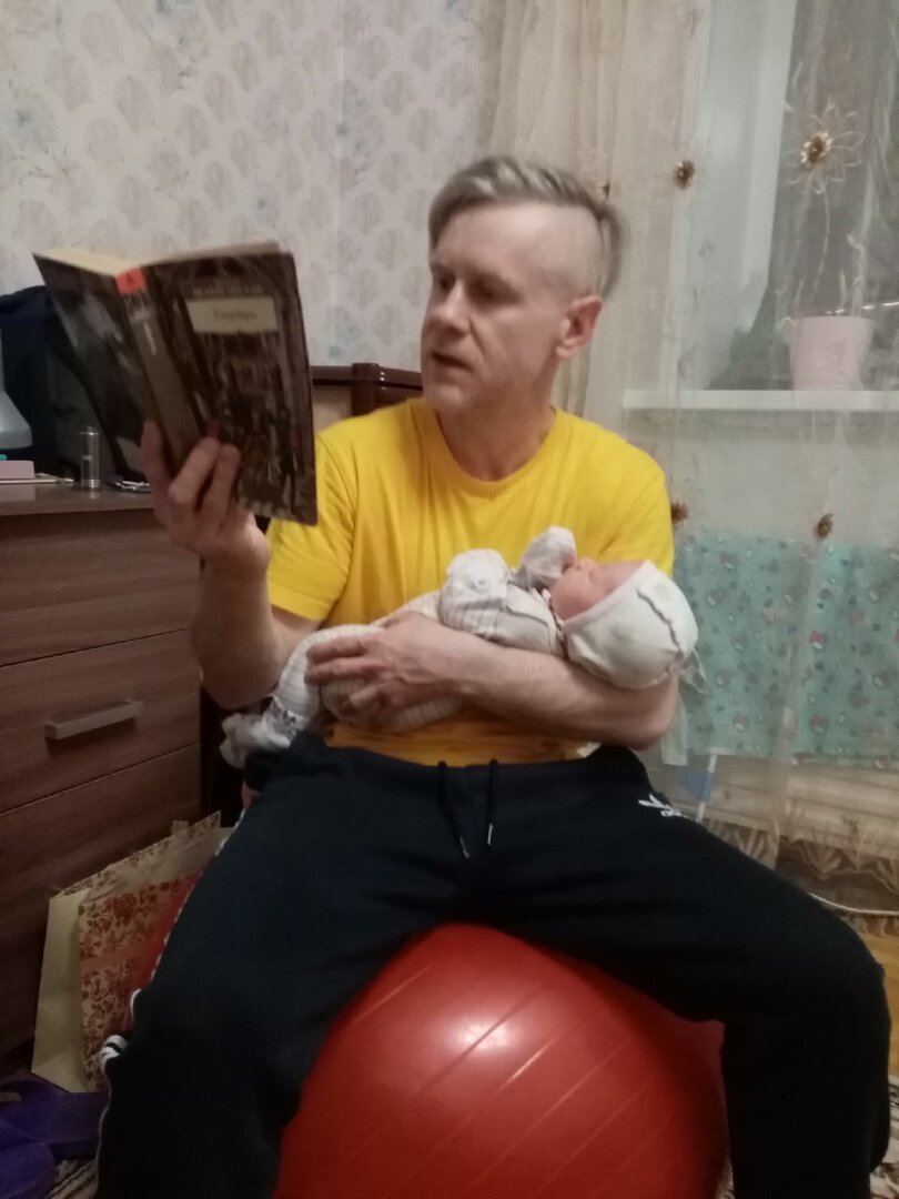 Муж качает ребенка и читает Макиавелли 