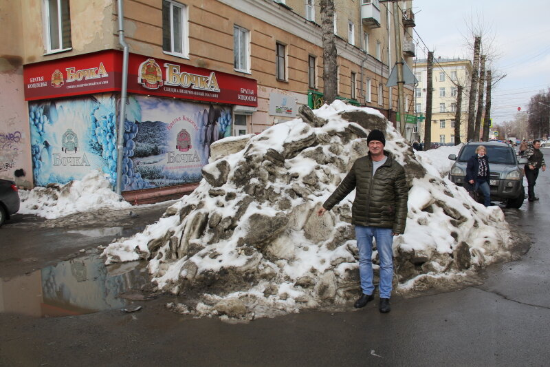 Е. Кротов у грязной снежной кучи на выезде из двора дома по ул. Дзержинского, 57