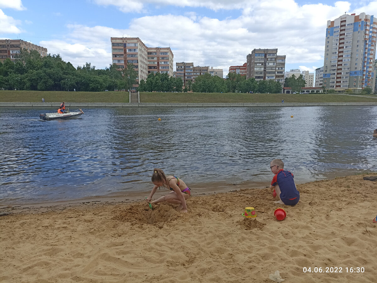 Дети играют у реки, а за ними с воды и с суши бдят спасатели. 