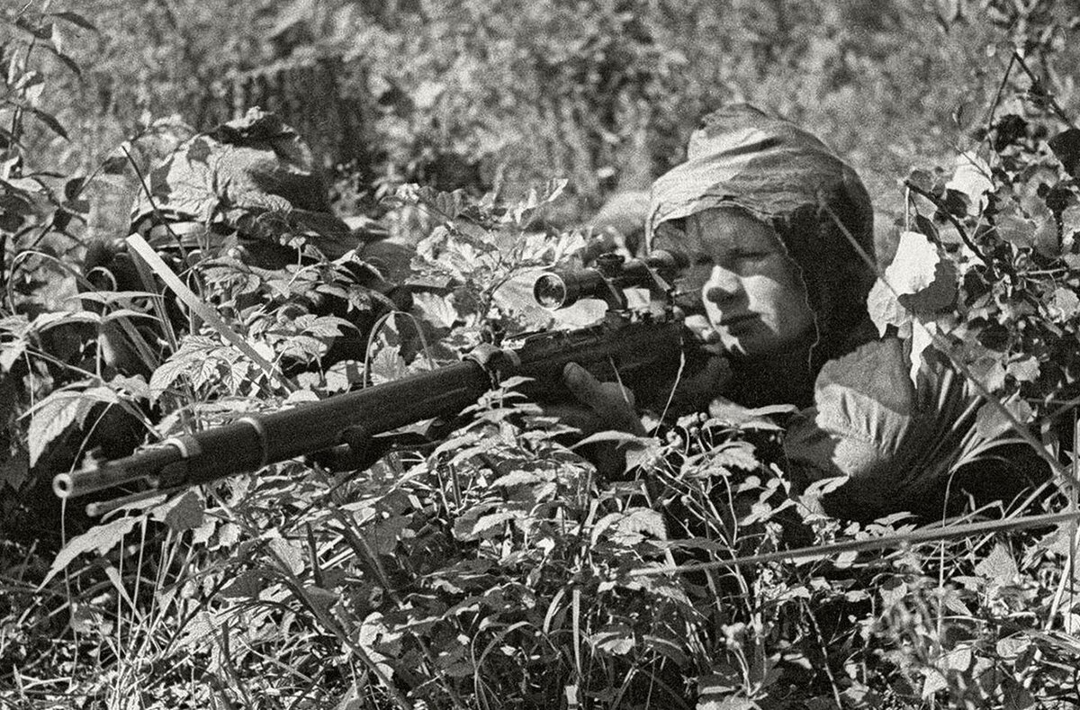 Снайпер в укрытии готовится к стрельбе.