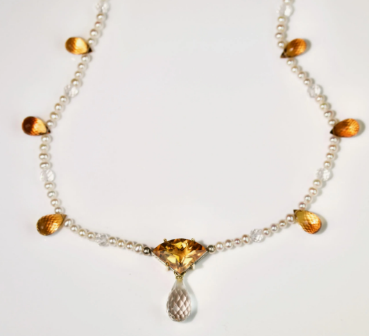 Цитрин триллионной огранки с кварцевым бриллиантом в оправе из желтого золота. Красиво сидит на нитке жемчуга, с бриолетовыми цитриновыми и кварцевыми бусинами.