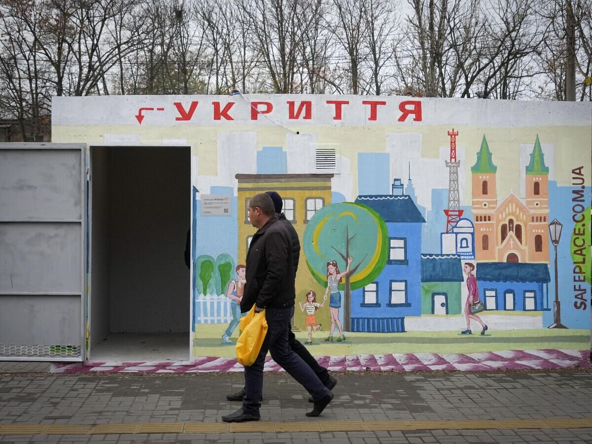    Люди проходят мимо бетонного навеса с надписью "укрытие", установленного на остановке общественного транспорта в Николаеве© AP Photo / Efrem Lukatsky