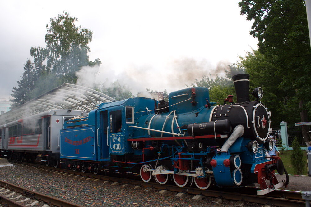 Когда-то это была Малая Горьковская железная дорога, впоследствии название сделали более простым – детская. Практически все здесь делают дети, под строгим присмотром взрослых. Когда-то я тоже мечтал работать на «железке», уж не знаю: к сожалению, или к счастью, но мечта не сбылась, а вот пассажиром я стал частым. Так что сделаем поправку на то, что сбылась но частично. По традиции в День защиты детей в Нижнем Новгороде открывается детская железная дорога. Она будет работать до самого конца лета, и совершать четыре рейса в день. А на открытие по традиции на линию поставили старинный паровоз