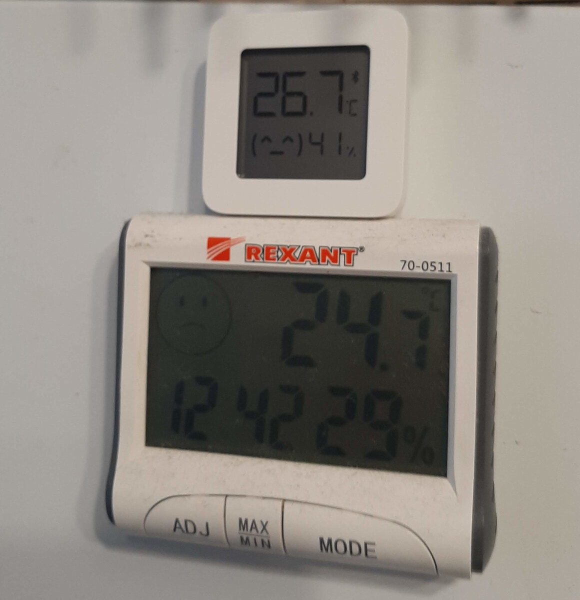 Верхний прибор - это датчик "умного дома" от Xiaomi:  в корпусе малыша помещён передатчик с технологией Bluetooth Low Energy (без Bluetooth Classical). 
У нижнего прибора ничего, кроме врущего датчика влажности, нет